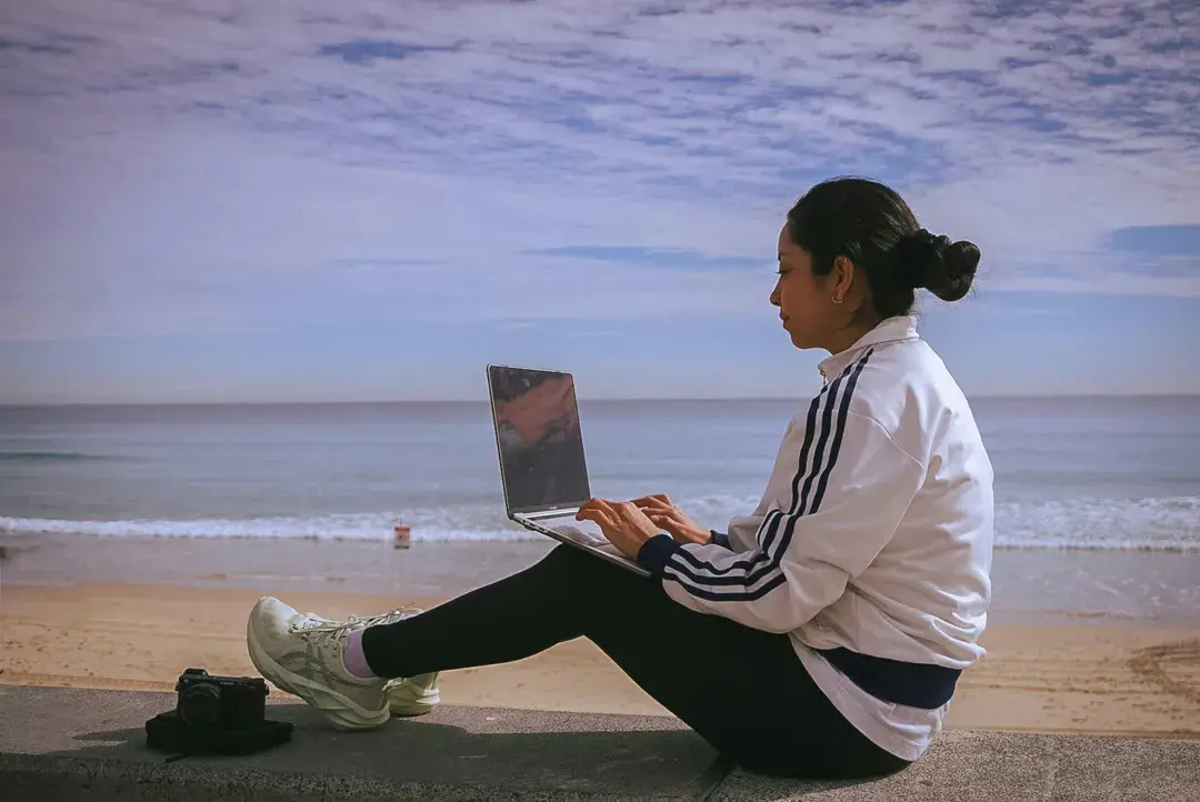 A coach working on a laptop by the sea