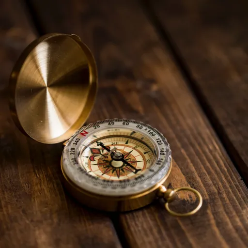 A brass compass on a wooden table